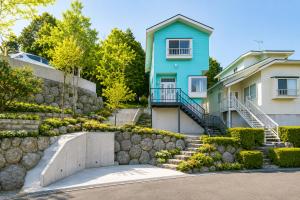 a blue house with a stone retaining wall and stairs at Fuji Nest Izu in Izunokuni