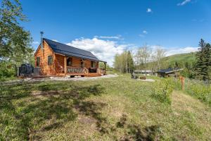 a wooden cabin in a field next to a grass field at River Retreat Kananaskis in Turner Valley