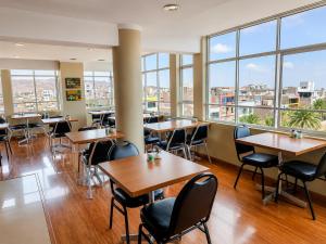 a restaurant with tables and chairs and large windows at Hotel Premier in Tacna