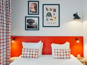 a bedroom with an orange headboard and framed pictures at Aparthotel Adagio Access Paris Vanves - Porte de Versailles in Vanves +33 photos