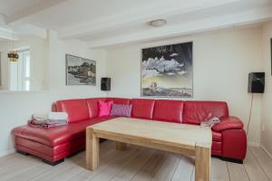 a red couch in a living room with a wooden table at Jógvansstova - 2BR House - Explore the North in Leirvík