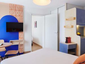 a bedroom with a white bed and a table and a room at Aparthotel Adagio Access Rennes Centre in Rennes