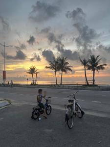 a little boy standing next to two bikes on a street at Khách Sạn Long Dung in Nam Khê