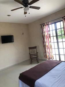 a bedroom with a bed and a chair and a ceiling fan at Gated house with garden and pool Mérida in Caucel