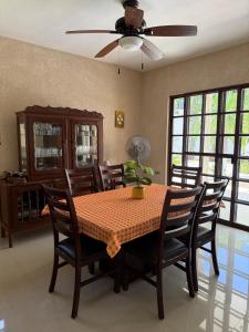 a dining room with a table with chairs and a ceiling fan at Gated house with garden and pool Mérida in Caucel