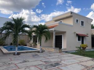 a house with a swimming pool and palm trees at Gated house with garden and pool Mérida in Caucel