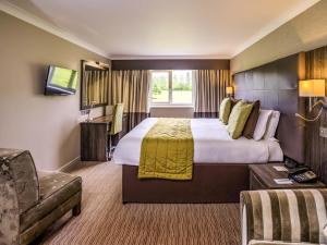 a hotel room with a large bed and a chair at Mercure Milton Keynes Hotel in Milton Keynes +91 photos