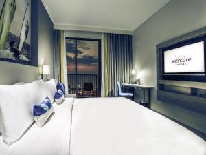 a hotel room with a large bed and a flat screen tv at Mercure Pattaya Ocean Resort in Pattaya
