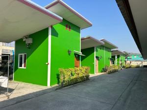 a green building with a driveway in front of it at เจิดจรัสรีสอร์ทโรงแรม24ชม in Chon Buri