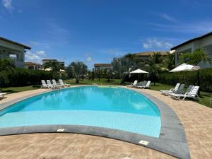 a large swimming pool with lounge chairs and umbrellas at Apartamento térreo com 3 quartos no Tree Bies- próximo do parque aquático infantil in Subaúma