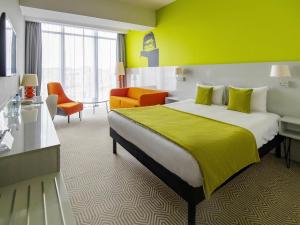 a hotel room with a bed and a yellow wall at Ibis Styles Wroclaw Centrum in Wrocław +114 photos