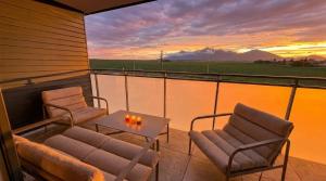 two chairs and a table on a balcony with a sunset at Bela Bonita in Spišská Belá