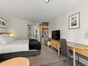 a hotel room with a bed and a desk and a computer at Novotel Queenstown Lakeside in Queenstown