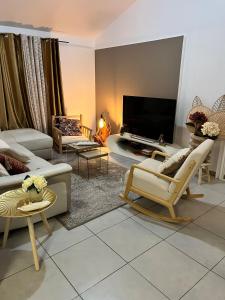 a living room with couches and a flat screen tv at Villa Odeyssia in Sainte-Anne