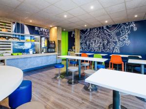 a restaurant with white tables and colorful chairs at Ibis Budget Marseille Timone in Marseille