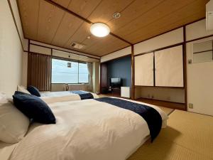 a bedroom with two beds and a television in it at Hotel Shin Makomo in Itako +48 photos