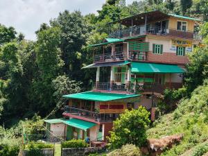 a tall building with green balconies on a hill at The Moon Light Home stay in Bhīm Tāl