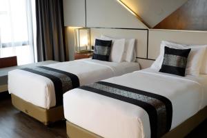 two beds in a hotel room with white and black pillows at Rayz UMM Hotel Malang in Malang +16 photos