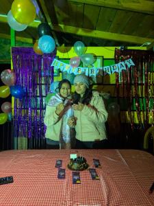 two women standing next to a table with a birthday at The Moon Light Home stay in Bhīm Tāl