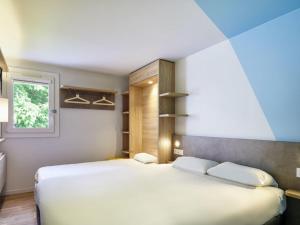 a bedroom with a large white bed and a window at ibis budget Bayonne in Bayonne