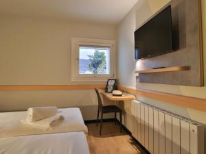 a hotel room with a bed and a desk with a television at Hotel ibis budget Aix Les Bains - Grésy in Grésy-sur-Aix