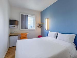 a hotel room with a large white bed and a window at ibis budget Curitiba Centro in Curitiba