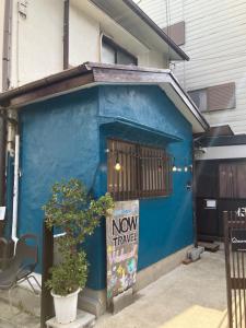 a blue building with a new triangle sign on it at Guest House NOW TRAVEL ShinOsaka 全室禁煙 子供不可 in Osaka