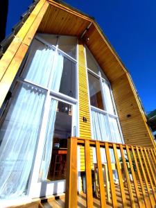 a house with a large window on a wooden deck at Villa Celyn Dieng cabin in Diyeng