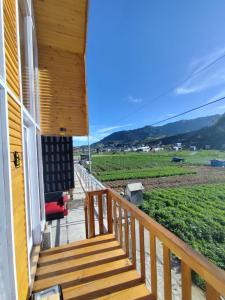 a porch of a house with a view of a field at Villa Celyn Dieng cabin in Diyeng +2 photos