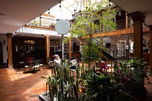 a room filled with lots of plants and tables at Hotel & Suites El Quijote in Cuenca