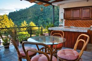 a patio with a glass table and chairs on a balcony at Finca del Valle in Valle de Bravo