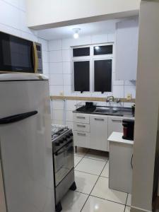 a white kitchen with a stove and a refrigerator at Apartamento central 1 quarto in Passo Fundo