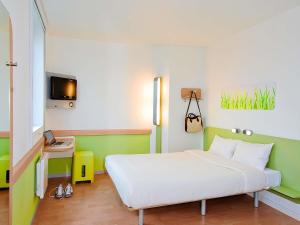 a bedroom with a white bed and a tv at Ibis Budget Roanne Hôtel in Roanne
