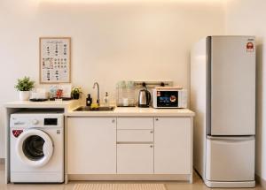 a kitchen with a refrigerator and a washing machine at Minimalist Studio Trefoil Setia Alam linked bridge to Mall and Convention Centre near to NIH Peninsula in Setia Alam