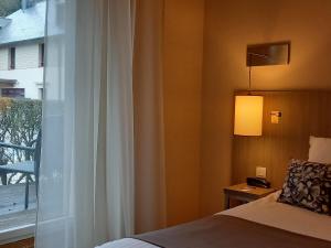 a bedroom with a bed and a window with a lamp at Mercure Dinan Port Le Jerzual in Dinan