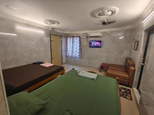 a bedroom with a bed and a couch and a television at SEYONE stay in Kanchipuram +5 photos