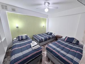 a bedroom with two beds and a ceiling fan at Hotel Simon II in Antofagasta