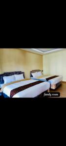 two beds in a hotel room with two at Griya Imafa Inn Batu in Tlekung +9 photos