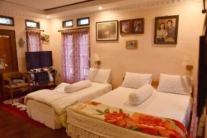 two beds in a room with pictures on the wall at Elle Maya Sari Residence in Kotabaru
