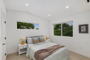 a white bedroom with a bed and two windows at Modern House in Seattle in Seattle