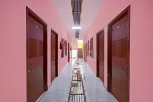 a corridor of a hallway with brown doors and tile floors at Hotel O Parthasarathyswamy Temple Formerly RKH Inn in Chennai