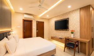 a hotel room with a bed and a desk and a television at Harvey's Suites in Gachibowli
