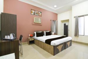 a bedroom with a bed and a desk in a room at Super Collection O Kalighat Metro Station Formerly RM Guest Home in Ālīpur +25 photos