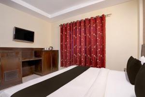 a bedroom with a bed and a desk and a television at Collection O Haridwar Railway Station Formerly Le Central in Haridwār +26 photos