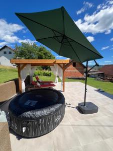 a large green umbrella sitting on a patio at Kuća za odmor Sedra - jacuzzi & sauna in Hrvatska Kostajnica