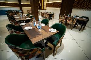 a restaurant with wooden tables and green chairs at Hotel Gharana Tree in Gaya