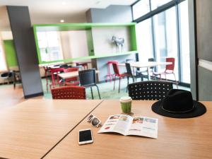 a hat sitting on a table with a book and a cell phone at ibis Styles Moulins Centre in Moulins