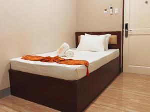 a bed with white sheets and an orange blanket on it at Emmie Hotel in Legazpi