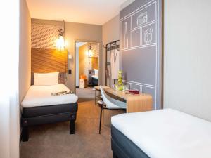 a hotel room with two beds and a desk at ibis Geneve Centre Lac in Geneva