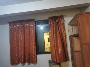 a window with red curtains in a room at Hostal Salome in Cochabamba